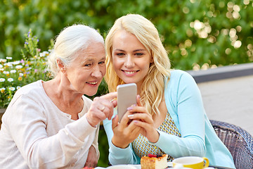 Image showing daughter and senior mother with smartphone at cafe