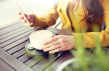 Image showing close up of woman texting on smartphone at cafe