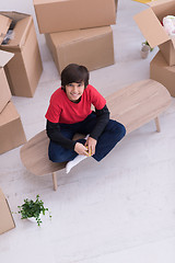 Image showing boy sitting on the table with cardboard boxes around him top vie
