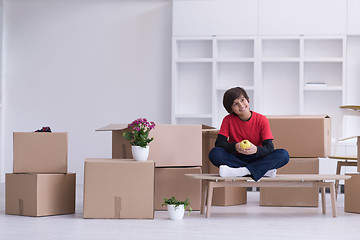 Image showing boy sitting on the table with cardboard boxes around him