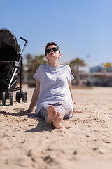 Image showing Young mother with sunglasses relaxing on beach