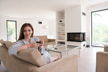 Image showing young woman in a bathrobe enjoying morning coffee