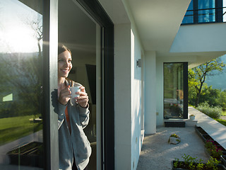 Image showing woman drinking coffee in front of her luxury home villa