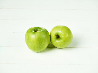 Image showing Shot of two fresh green apples with green leaf on a table.