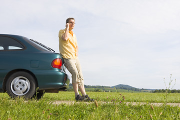 Image showing Man talking on cell phone beside his car