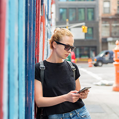 Image showing Woman using smartphone against colorful graffiti wall in New York city, USA.