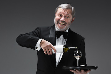 Image showing professional waiter in uniform is serving wine