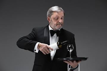 Image showing professional waiter in uniform is serving wine