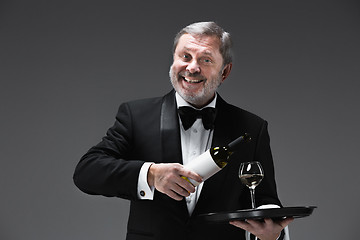 Image showing professional waiter in uniform is serving wine