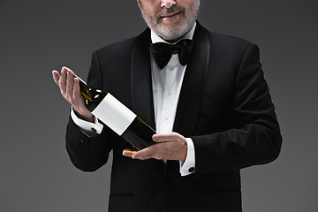 Image showing professional waiter in uniform is serving wine