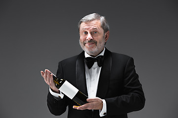 Image showing professional waiter in uniform is serving wine