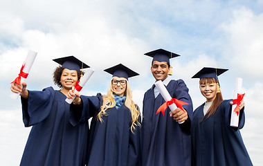 Image showing happy students in mortar boards with diplomas