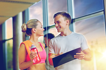 Image showing smiling young woman with personal trainer in gym