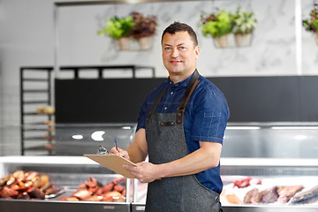 Image showing seller at fish shop writing to clipboard