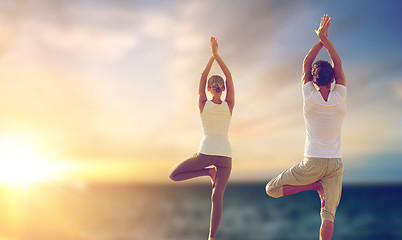 Image showing happy couple making yoga tree pose over sea