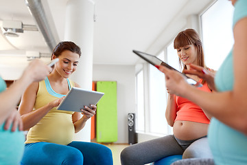 Image showing happy pregnant women with tablet pc in gym