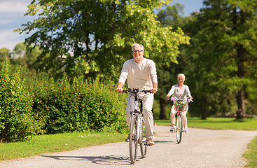 Image showing happy senior couple riding bicycles at summer park