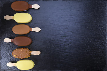 Image showing Ice cream on stick covered with chocolate on black