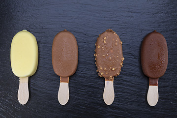 Image showing Ice cream on stick covered with chocolate on black slate 