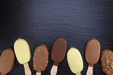 Image showing Ice cream on stick covered with chocolate on black