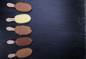 Image showing Ice cream on stick covered with chocolate on black