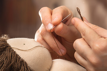 Image showing hands of woman sewing hair to the Waldorf doll