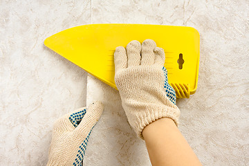 Image showing hands smoothing wallpaper with scraper on the wall