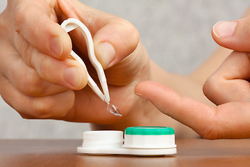 Image showing woman hands putting on contact lenses