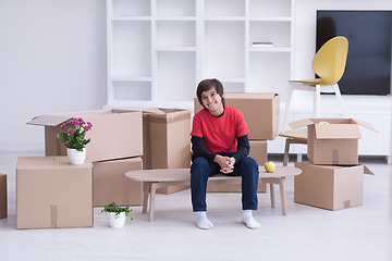 Image showing boy sitting on the table with cardboard boxes around him