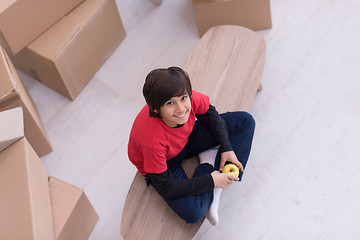 Image showing boy sitting on the table with cardboard boxes around him top vie