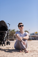 Image showing Young mother with sunglasses relaxing on beach