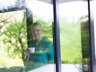 Image showing young woman drinking morning coffee by the window