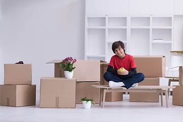 Image showing boy sitting on the table with cardboard boxes around him