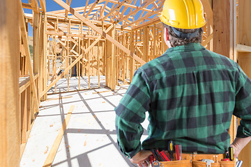 Image showing Contractor Standing Inside Construction Framing of New House.