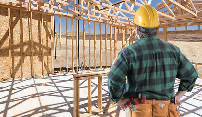 Image showing Contractor Standing Inside Construction Framing of New House.