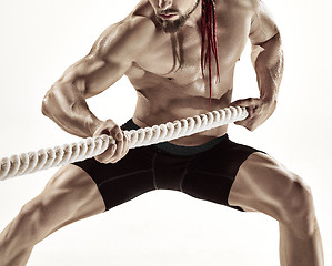 Image showing Attractive muscular man working out with heavy ropes.