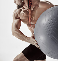 Image showing Muscular man holding fitness ball, standing isolated on white