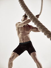 Image showing Attractive muscular man working out with heavy ropes.