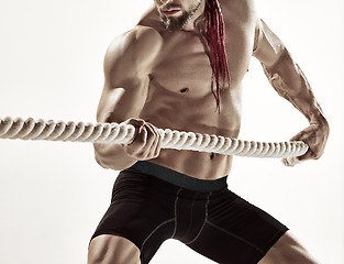 Image showing Attractive muscular man working out with heavy ropes.