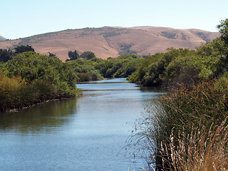 Image showing waterway slough with hills grass reeds and blue sky