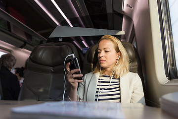 Image showing Businesswoman communicating on mobile phone while traveling by train.