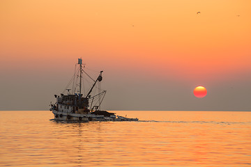 Image showing Fishing boat sailing into sunset.