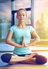 Image showing happy woman meditating in lotus pose on mat