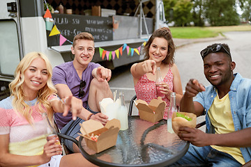 Image showing happy friends with drinks eating at food truck