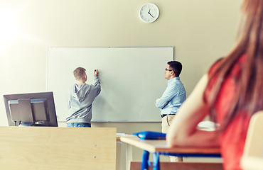 Image showing teacher and student writing on board at school