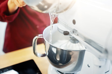 Image showing chef pouring ingredient from pot into mixer bowl