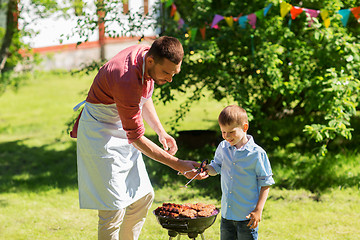 Image showing father and son cooking meat on barbecue grill