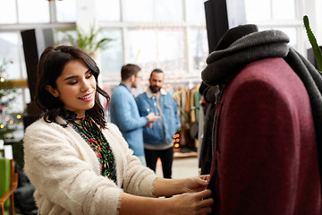 Image showing happy woman choosing clothes at clothing store