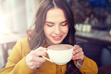 Image showing happy woman drinking cocoa at city street cafe