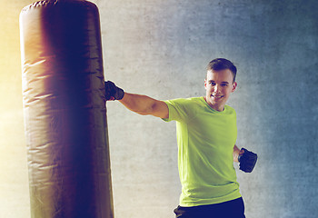 Image showing young man in gloves boxing with punching bag